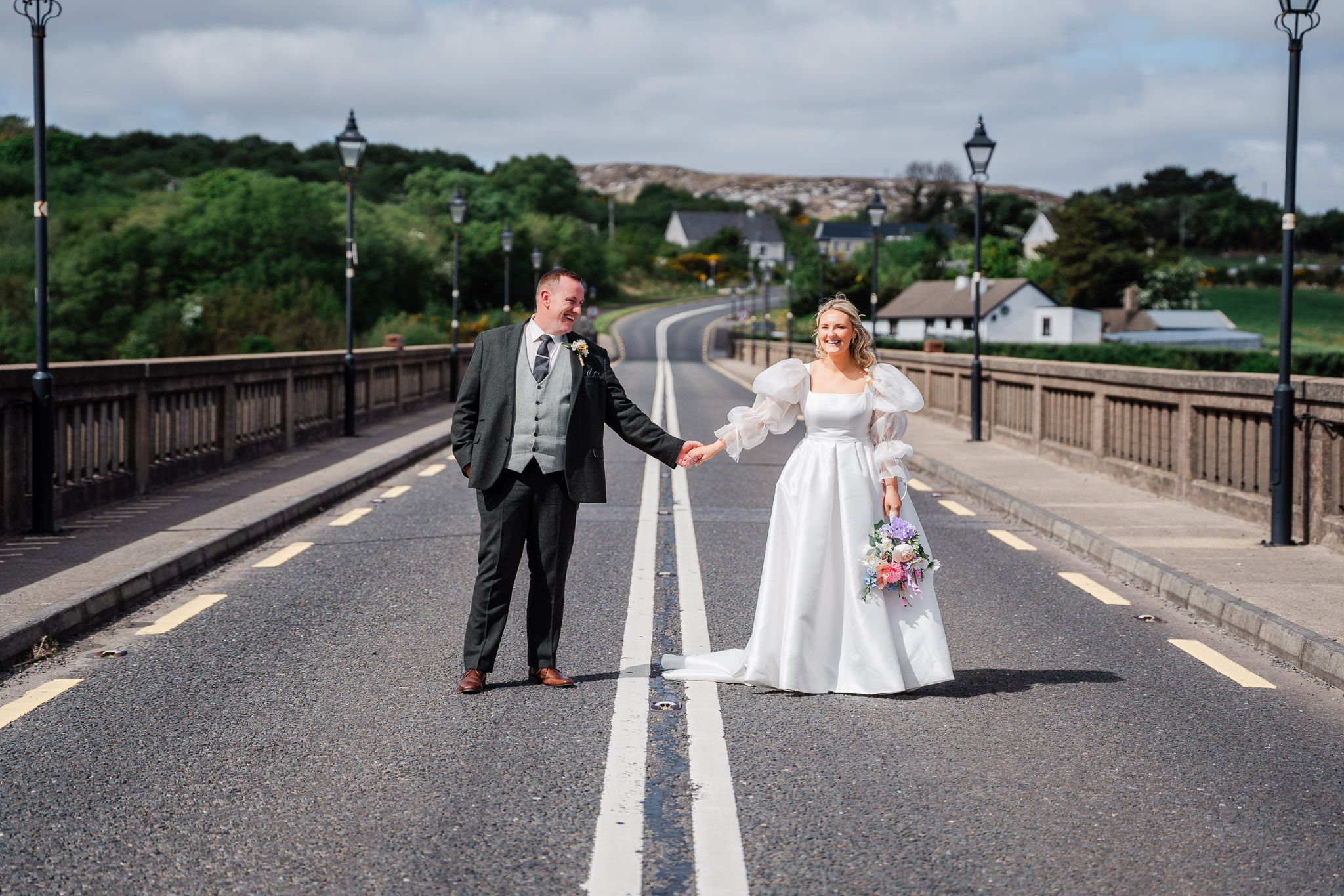 A bride and groom hold hands on Gwebarra Bridge, County Donegal